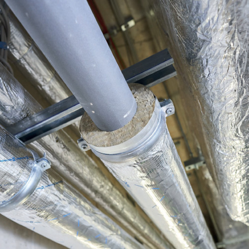 Foil-faced lagging pipe insulation wrapped around industrial pipework.
