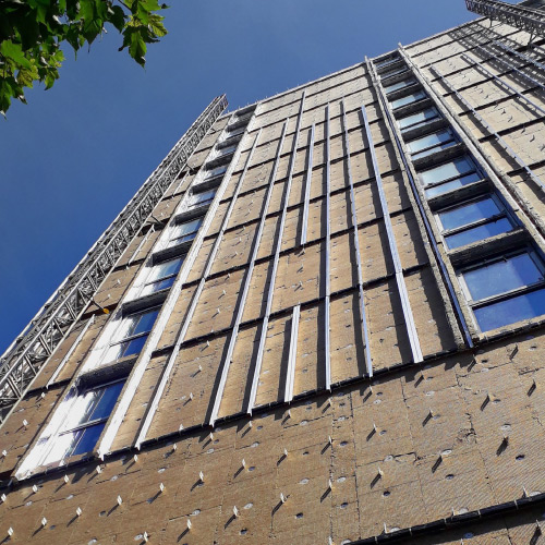 High-rise building exterior being fitted with a grid for external wall insulation panels.