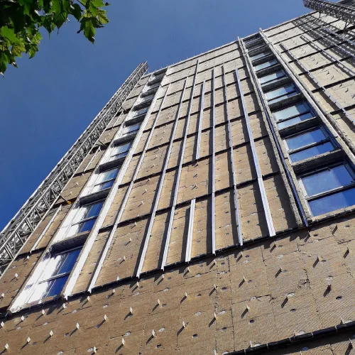 High-rise building exterior being fitted with a grid for external wall insulation panels.