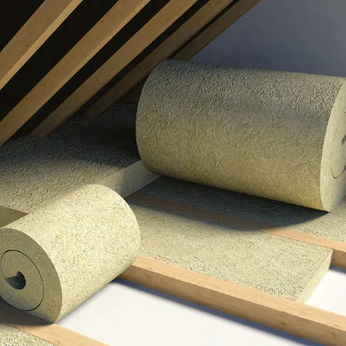 Rolls of mineral wool loft insulation laid out between wooden joists in an attic.