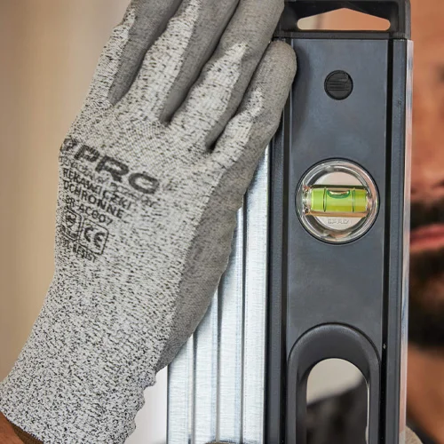 Gloved hand holding a spirit level alongside other building tools.