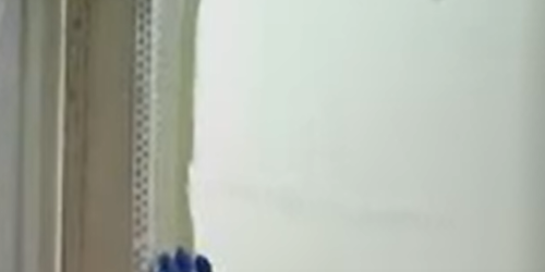 Close-up of a person plastering a white wall corner