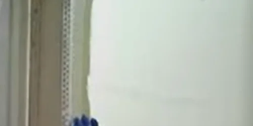 Close-up of a person plastering a white wall corner