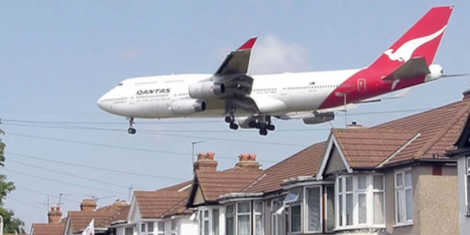 Commercial airplane flying low over residential rooftops