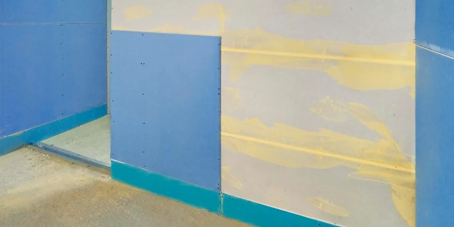 Installation of blue Knauf Safeboard X-ray shielding plasterboard on a metal stud wall frame