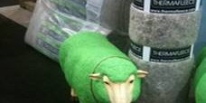 Green sheep standing next to rolls of wool insulation