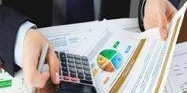 Person calculating finances with a calculator and charts