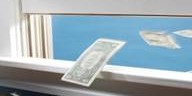 Banknotes flying out of an open window