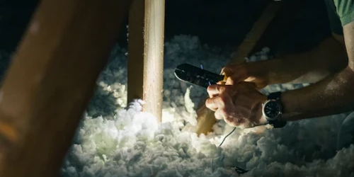 Person installing insulation material in a loft space
