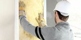 Construction worker applying yellow insulation to a wall