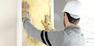 Construction worker applying yellow insulation to a wall