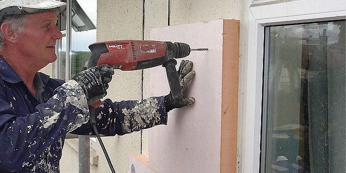 Construction worker installing insulation boards on an exterior wall
