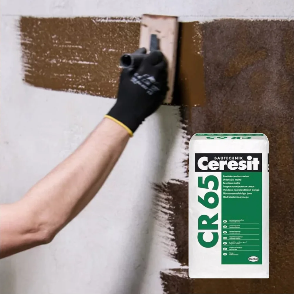 Worker applying a black damp proofing treatment to the base of a brick wall.